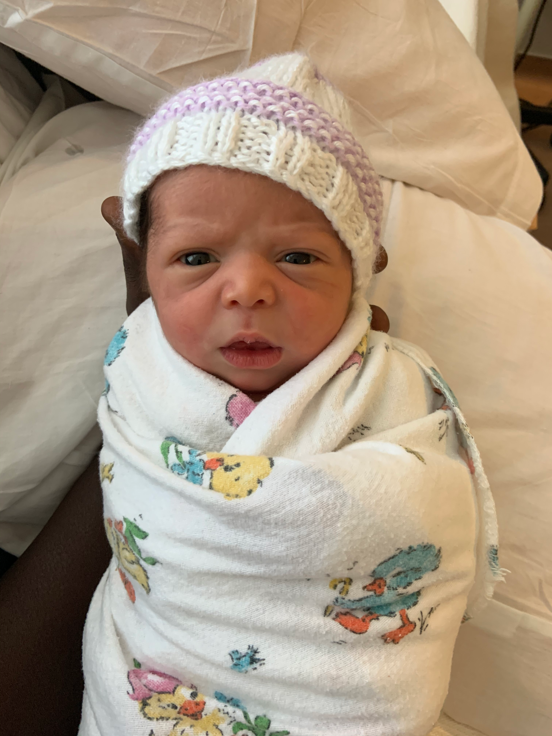 infant swaddled with hat on